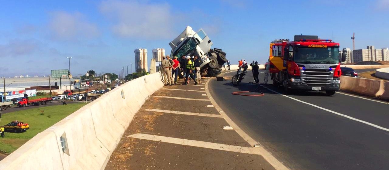 Carreta tomba sobre mureta, por pouco não cai debaixo de viaduto 